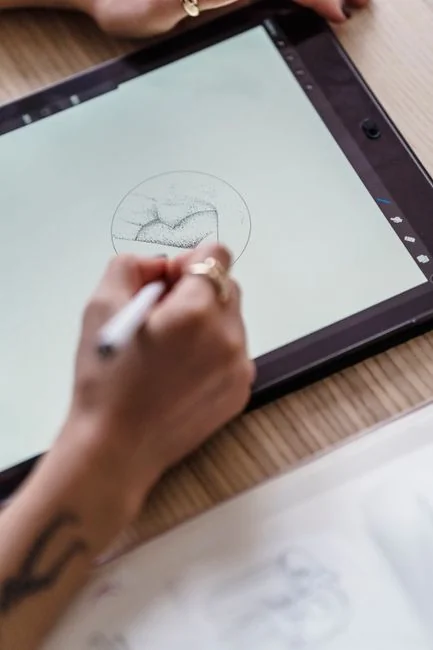 Deux collègues collaborent sur un projet de design autour d’un ordinateur portable et de nuanciers, installés à une table en bois.